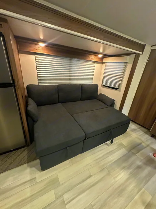 Modern RV rental living space featuring a dark gray sectional sofa that converts to a bed and offers hidden storage.. Cruiser RV MPG 2500bh 2024