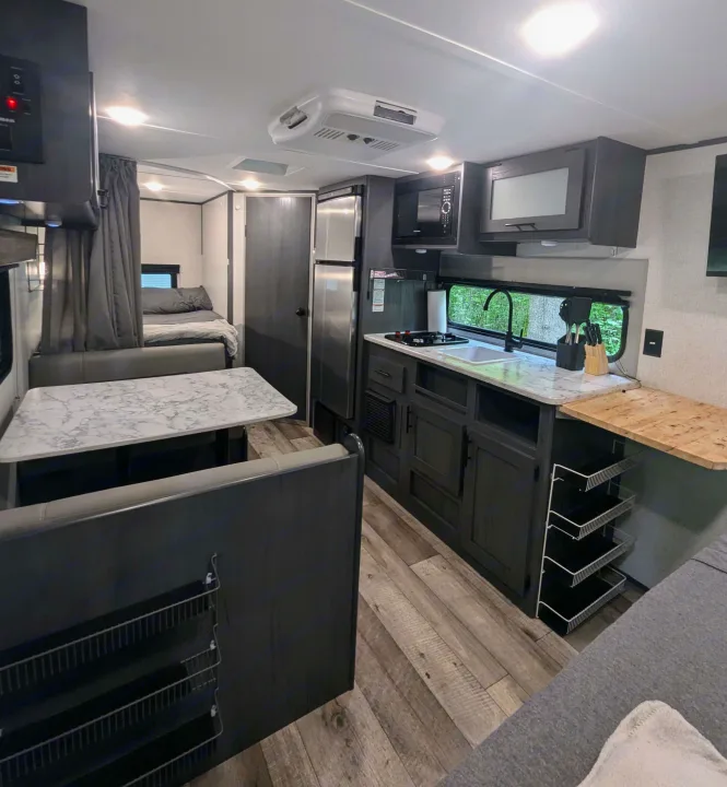 A spacious-looking RV rental interior with a fully equipped kitchen, dining booth, and rear bedroom area visible.. Aspen Trail LE 2022