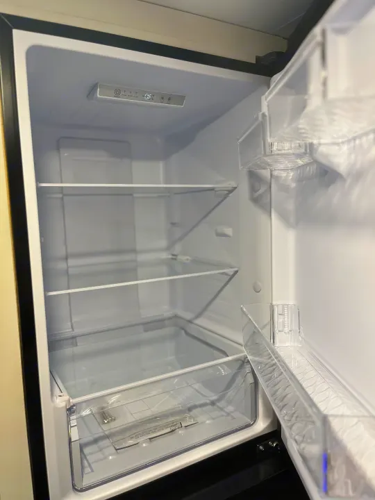 Empty and clean refrigerator interior in an RV rental, showing adjustable shelves and clear door storage.. Highland Ridge Open Range 2025