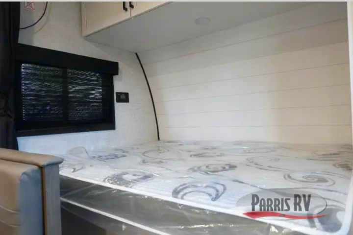 Inside an RV rental: Fresh bed with plastic, window blind, and modern shiplap wall design, ready for adventure.. Highland Ridge Open Range 2025