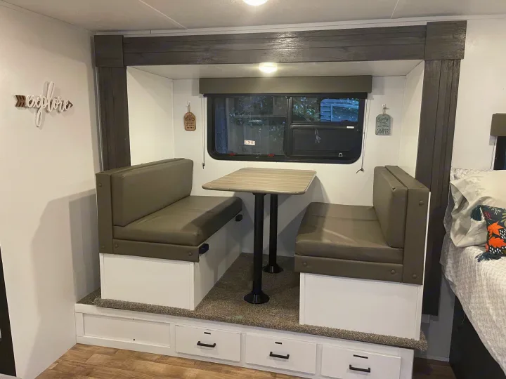RV rental: Compact dinette with olive upholstered booths, central table, and base storage drawers.. Keystone RV Hideout 2021