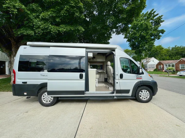This silver RV rental with its side door open shows a bright interior, perfect for travel and road trip adventures.. Thor Tellaro 2022