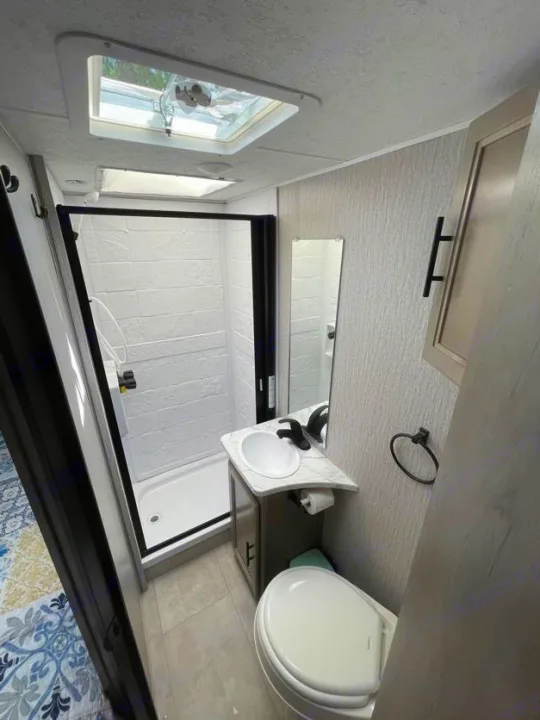 RV rental bathroom with shower, toilet, sink & skylight. Compact, modern, & ready for your adventures.. Forest River Coachmen Crosstrail 2023