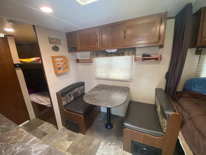 RV rental interior with a cozy dinette, overhead cabinets, bunk beds, and a sleeping area.. Jayco Jay Flight SLX 2016