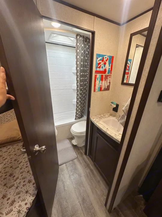 RV rental bathroom with shower, toilet, and sink. Door reveals bedroom. Compact and functional space.. Jayco Jay Flight SLX 2019