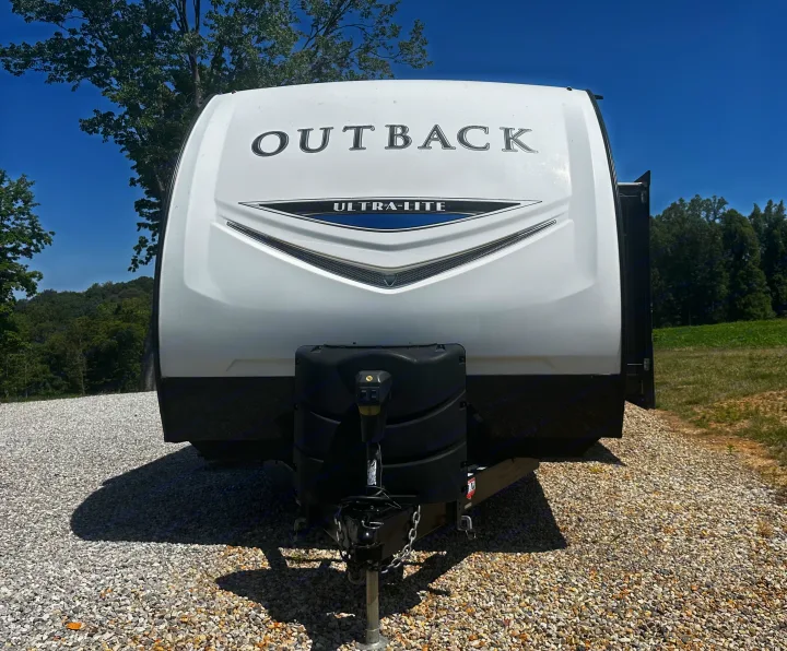 Front of a white Outback Ultra-Lite travel trailer, parked on gravel. Consider this RV rental for your next trip.. Keystone RV Outback Ultra-Lite 2018