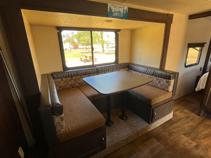 This RV rental features a cozy dinette with a large window offering a view of the campsite, perfect for meals and relaxation.. Forest River Wildwood X-Lite 2018