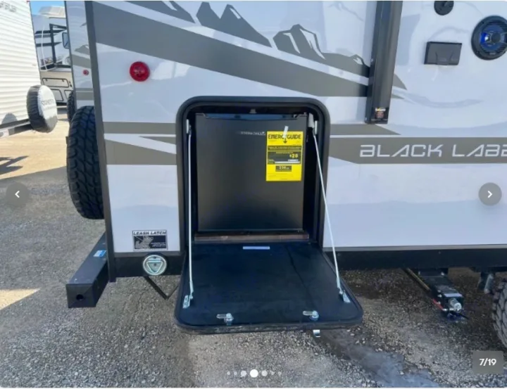 An RV rental showing an open exterior compartment revealing a mini-fridge, with a leash latch below. Ideal for outdoor adventures.. Forest River Cherokee Wolf Pup 16KHWBL 2024