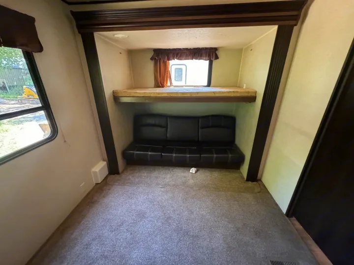 RV rental interior: bunk bed, black sofa, and a window with an outdoor view. Carpeted floor.. Forest River Salem Villa Classic Destination 2017