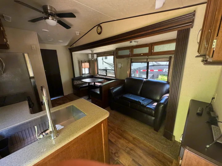 Full interior view of an RV rental: kitchen with sink, dining booth, and living area with leather sofa. Spacious & well-equipped.. Forest River Salem Villa Classic Destination 2017