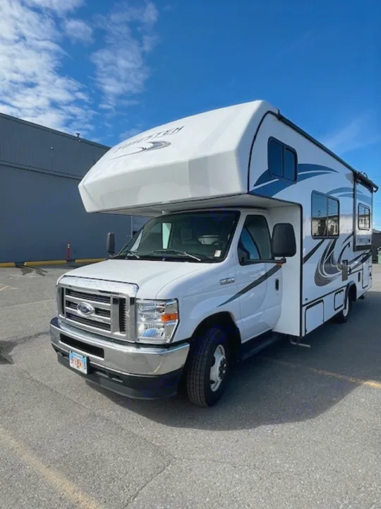 Spacious white Ford Class C RV, likely an rv rental, parked on asphalt under a blue sky, ready for adventure.. Forest River Forester 2022