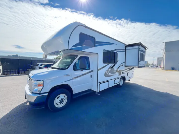 A white Class C motorhome rental, with a side slide-out extended, is parked in a sunny outdoor lot.. Forest River Forester 2022