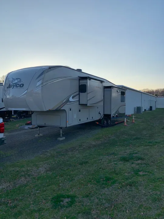 This Jayco Eagle fifth-wheel RV rental is fully set up with slide-outs extended, parked near storage buildings.. Jayco Eagle 2020