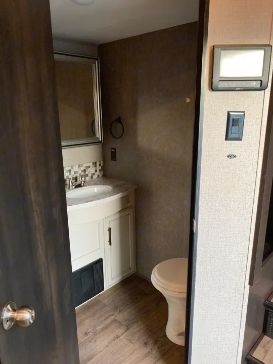 Compact RV rental bathroom with a sink, vanity, mirror, and toilet for efficient space.. Jayco Eagle 2020