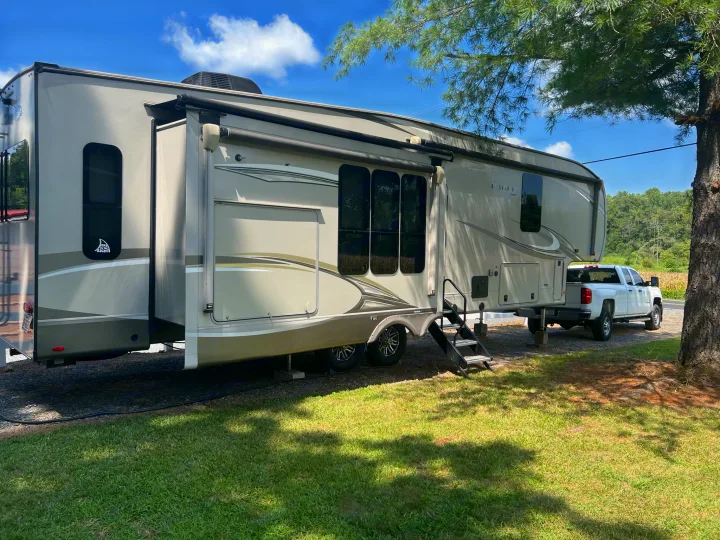 Spacious fifth-wheel RV rental set up with slide-outs extended, connected to a white pickup truck. Sunny outdoor scene.. Jayco Eagle 2020