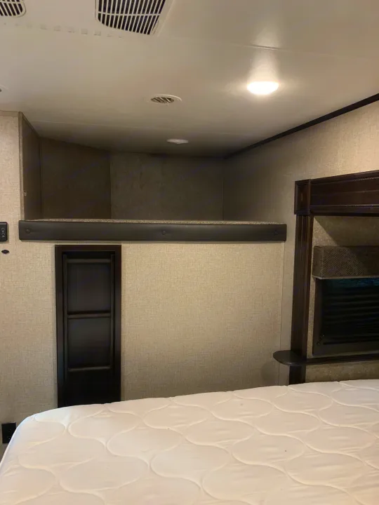 Cozy RV rental bedroom featuring a comfortable main bed and an overhead bunk/loft with ladder access.. Jayco Eagle 2020