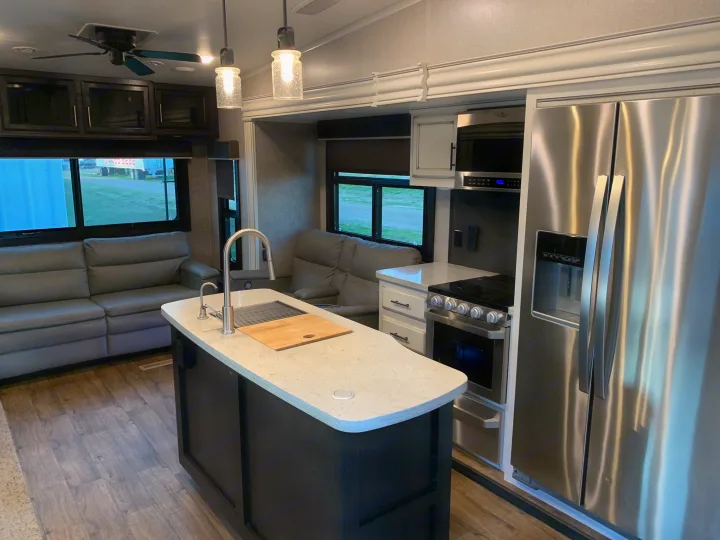 Modern RV rental interior: kitchen island, stainless steel fridge/stove, and cozy sofa living space. Perfect for your next adventure.. Jayco Eagle 2020