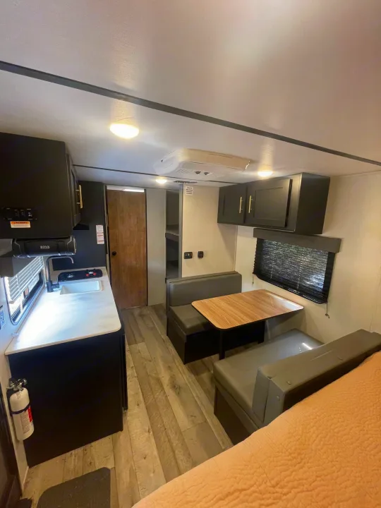 Explore this well-appointed RV rental interior: functional kitchen, dining booth, and sleeping space. Ideal for travel.. Keystone RV Springdale 2022