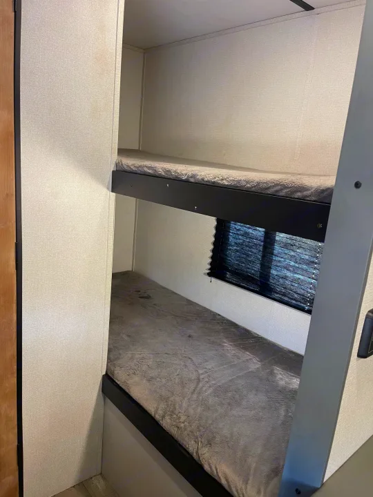 RV rental with cozy bunk beds, featuring a window and light interior walls for comfortable sleeping.. Keystone RV Springdale 2022