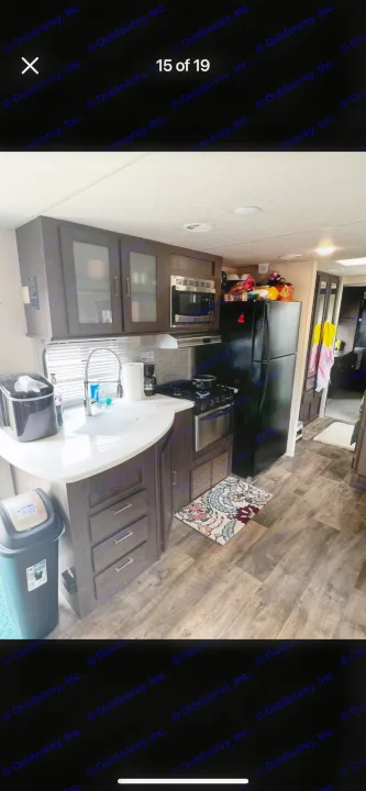 Modern RV rental kitchen featuring a full-size fridge, microwave, stove, sink, and stylish dark wood cabinets.. Forest River Salem 2018