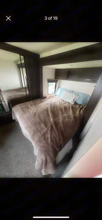 Cozy RV rental bedroom with bed, mirrored closet, window, and overhead cabinets for your travels.. Forest River Salem 2018