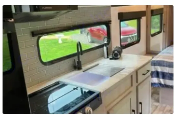 Explore in style! This RV rental boasts a clean, modern kitchen with subway tile, sink, and stovetop, ready for your next adventure.. Dutchmen Kodiak SE 2024