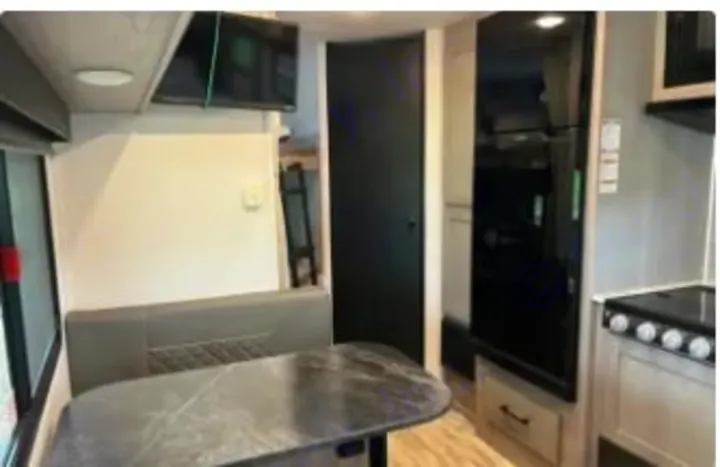 This RV rental shows a modern interior with a dinette, kitchen, fridge, and bunk bed access, perfect for your next road trip adventure.. Dutchmen Kodiak SE 2024