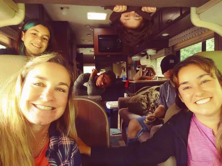 RV rental fun! A happy group of 6, including two women taking a selfie, smiles inside their cozy RV, one hangs upside down.. Thor Four Winds 2019