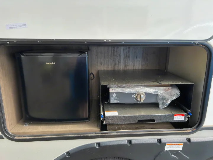 RV rental outdoor kitchen: a Hotpoint mini-fridge and pull-out Capital griddle, ready for outdoor cooking.. Keystone RV Cougar 2023