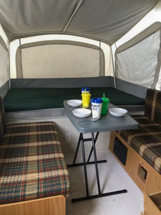 Inside an **RV rental**: a cozy pop-up camper interior with a dining area & bed. Perfect for camping adventures.. Coleman Destiny Taos 1999