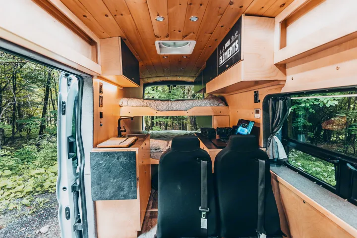 Step inside this custom camper van, an ideal RV rental. It features bunk beds, a workstation, and a kitchen, all immersed in nature.. Ford Van 2023