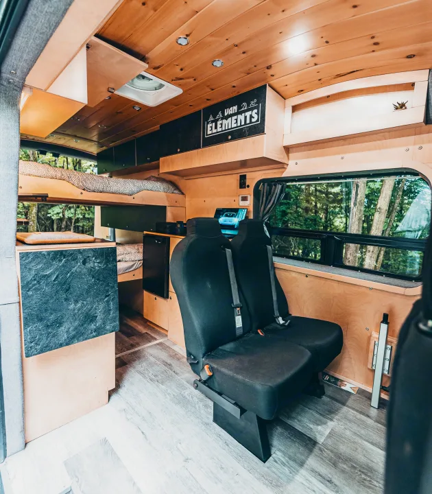 VAN ÉLÉMENTS rv rental: bespoke wood interior with passenger seats, bunk bed, and scenic forest views for adventures.. Ford Van 2023