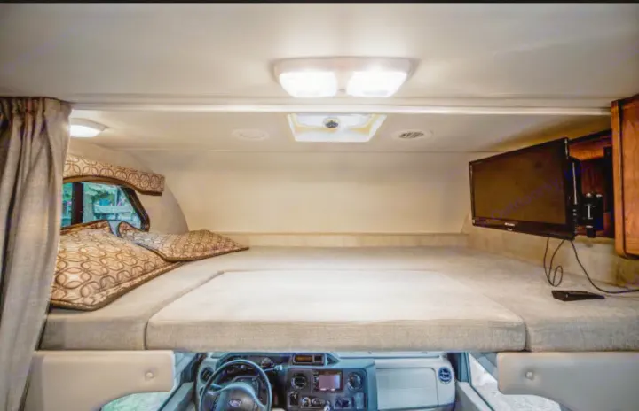 Spacious RV rental cab-over bunk area with comfy bed, TV, and window. Ideal for travel comfort.. Other Four Winds 2013