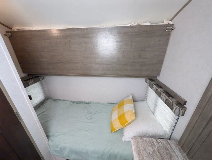 Cozy rv rental sleeping area featuring a bunk bed, green blanket, and yellow pillow for comfortable travel.. Forest River R Pod 2018