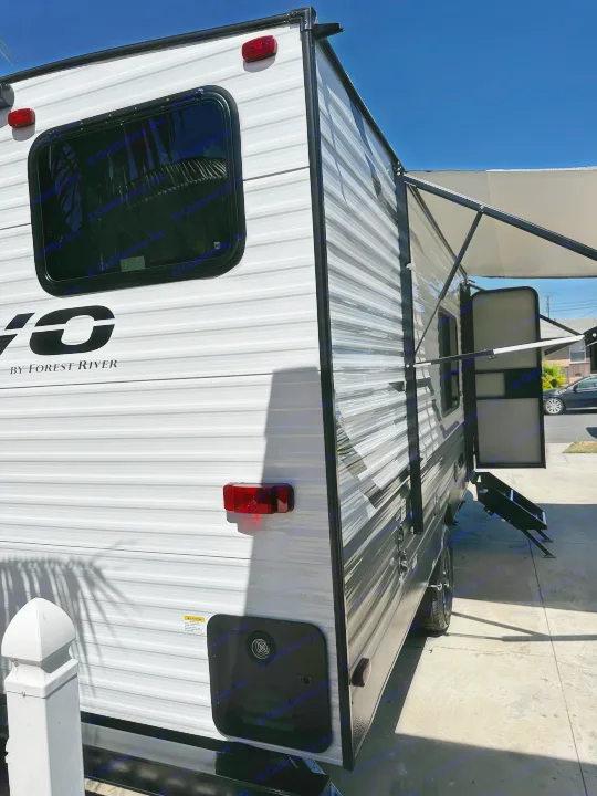 Side view of a white Forest River RV rental with its awning extended, parked on concrete under a clear sky.. Forest River EVO 2024