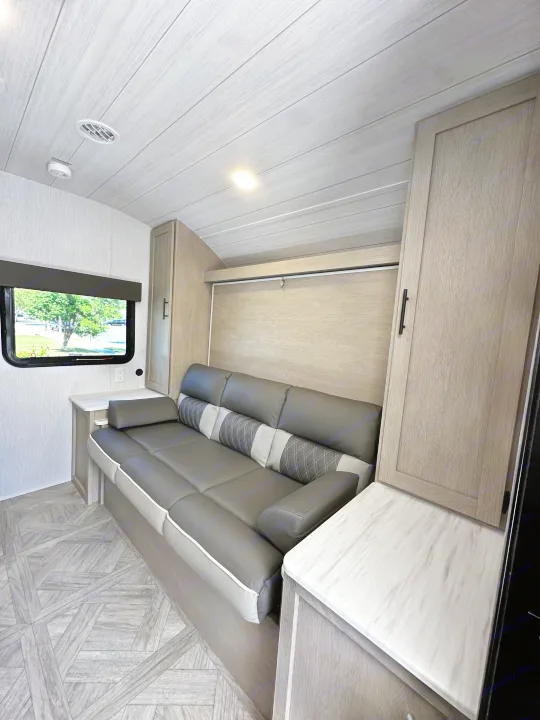 Modern RV rental interior featuring a comfortable sofa, convertible bed, and light wood finishes.. Forest River EVO 2024