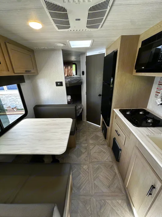 Bright RV rental interior with dinette, full kitchen, fridge, microwave, bunks. AC and wood-patterned floor.. Forest River EVO 2024