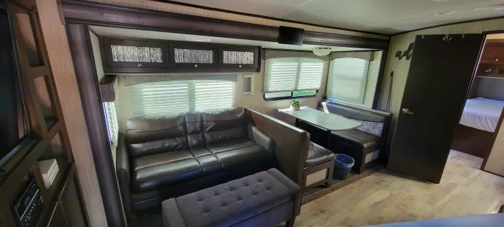 Enjoy this inviting RV rental interior, featuring a cozy sofa, dining booth, and private bedroom.. Heartland Sundance 2019