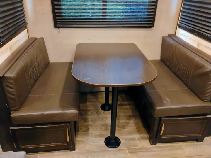 Cozy RV rental dinette: dark brown booth seating with a table & storage, ideal for dining in your motorhome.. Jayco Jay Feather 2021