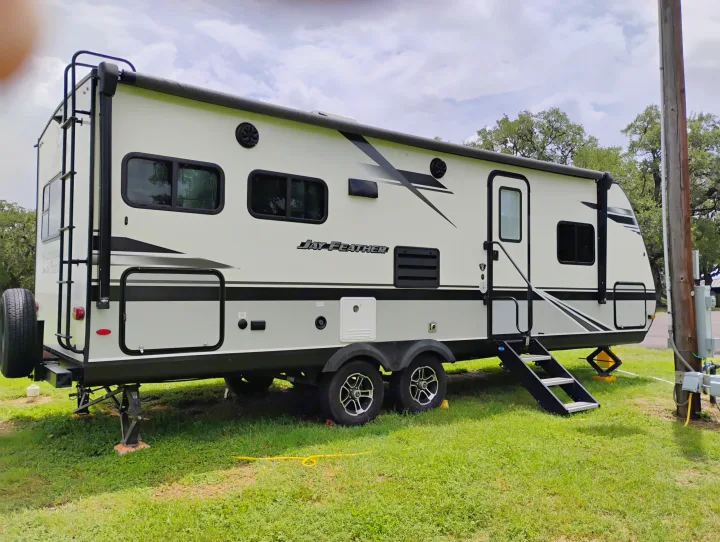 A white and grey Jay Feather travel trailer, parked at a campsite, ready for an RV rental adventure.. Jayco Jay Feather 2021