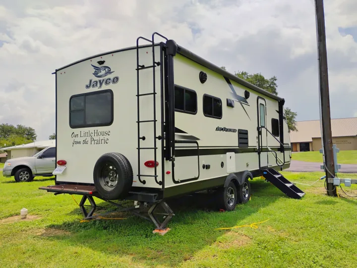 This Jayco travel trailer, an ideal RV rental, sits on green grass with power hookups, ready for your next adventure.. Jayco Jay Feather 2021