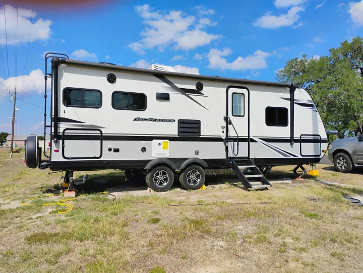 A modern Jay Feather RV rental is parked and set up at a sunny outdoor campsite under a blue sky.. Jayco Jay Feather 2021