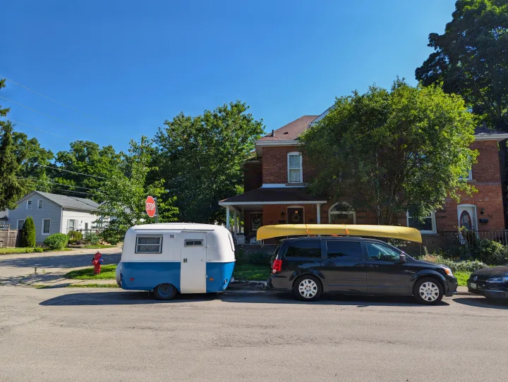 Sunny street scene with a charming blue & white **RV rental** camper and a minivan carrying a yellow canoe.. Boler Boler 1300 1974