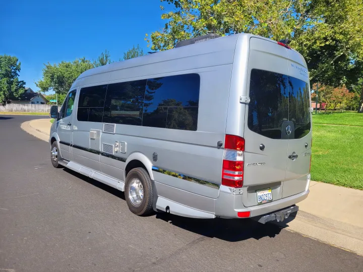 Silver Winnebago Sprinter touring coach, available for RV rental, seen parked on a sunny street.. Winnebago Era 2016