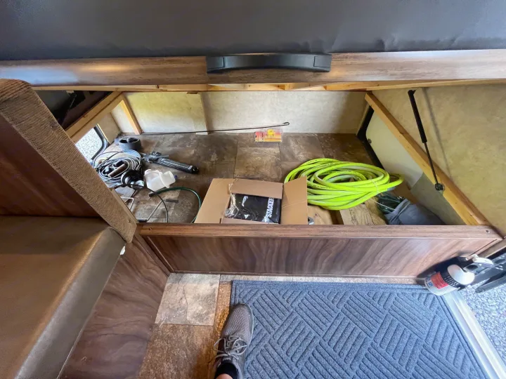 RV rental interior: open storage compartment under seating, filled with a green hose, box, and tools. Ready for travel!. Clipper Clipper Trailer 2016