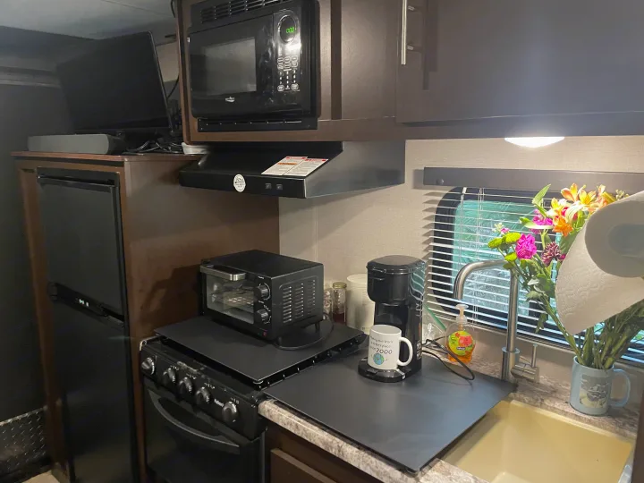 RV rental kitchen featuring a microwave, fridge, stove, toaster oven, coffee maker, and sink, highlighting a functional space.. KZ Sportsmen 2019