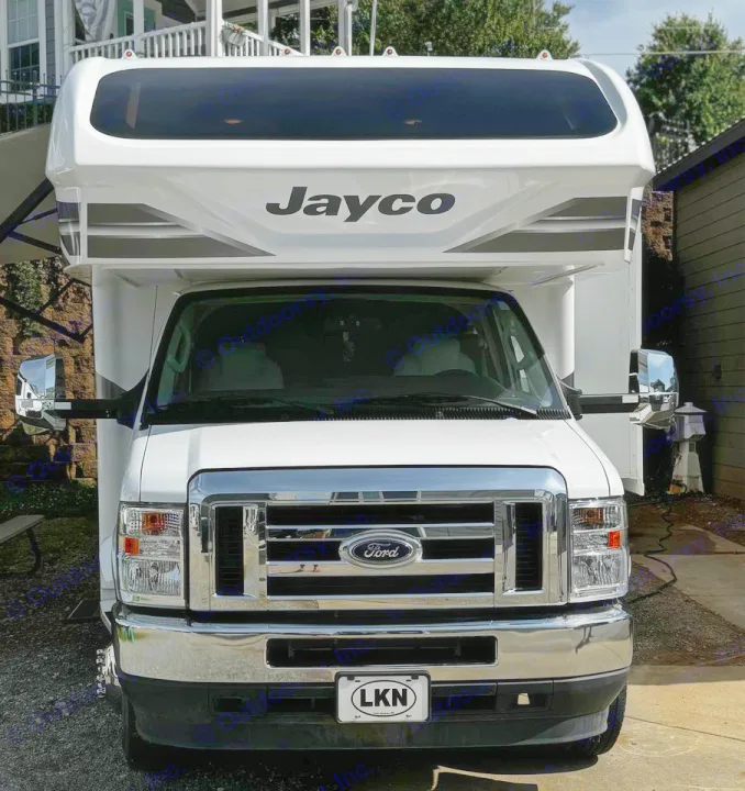 A large, white Jayco motorhome, a Ford Class C RV rental, stands ready for travel. Chrome grille visible.. Jayco Greyhawk 2021