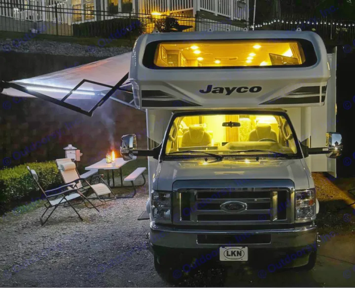 Night scene: Bright RV rental, extended awning, chairs & fire pit create a cozy camping spot. Ideal for outdoor adventures.. Jayco Greyhawk 2021
