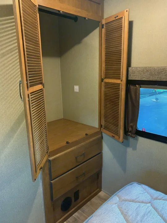 RV rental: Open louvered wardrobe reveals hanging rod & drawers. A comfortable bed and window are also visible.. Reflection BHT33 2018