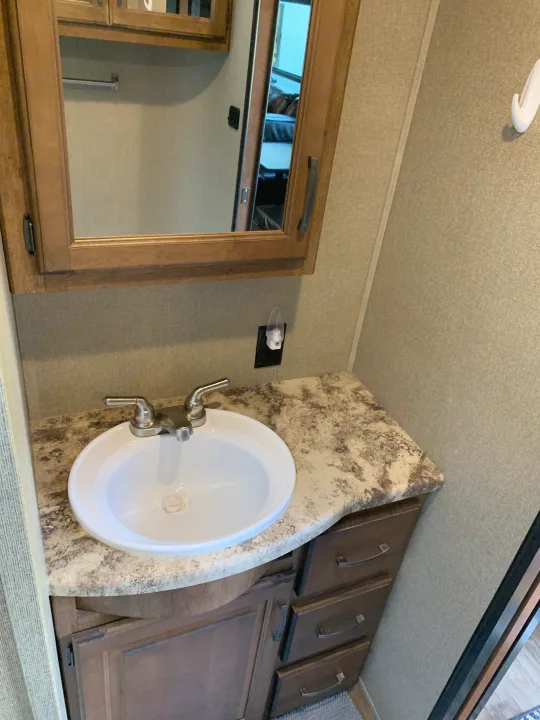 RV rental bathroom featuring a white sink, faucet, wood mirror, patterned vanity, and nightlight.. Reflection BHT33 2018